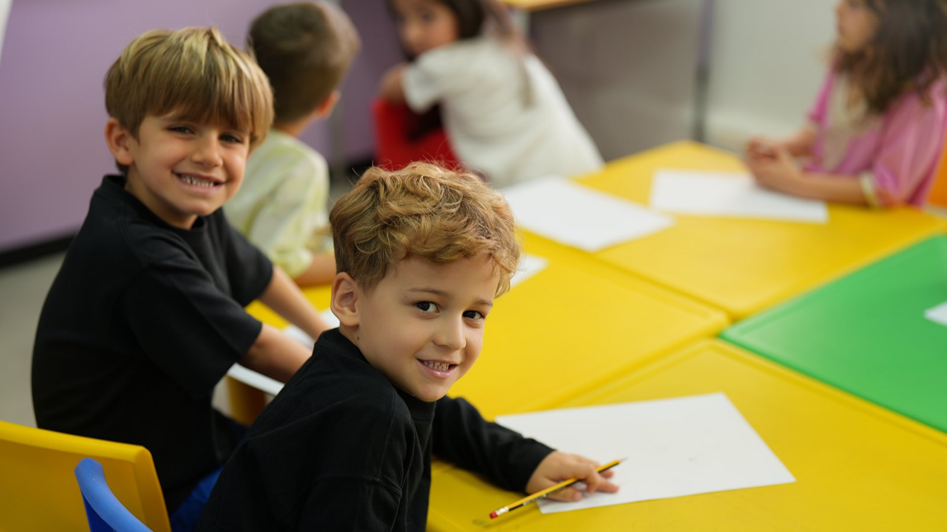 Young children writing at a classroom table